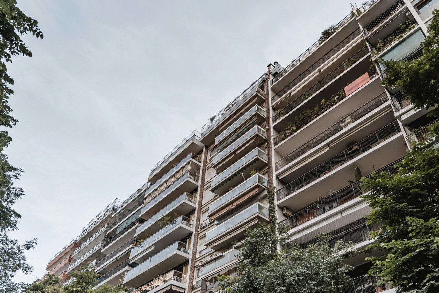 Multi-storey residential building with balconies, viewed from street level